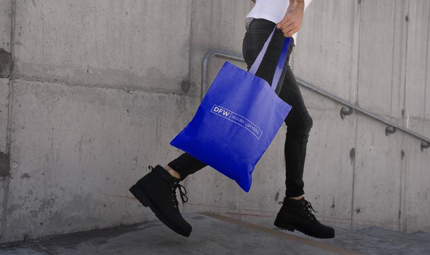 man carrying DFW Injury Lawyers tote bag